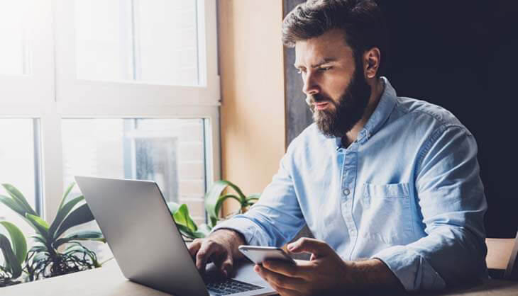 Mann sitzt vor Laptop
